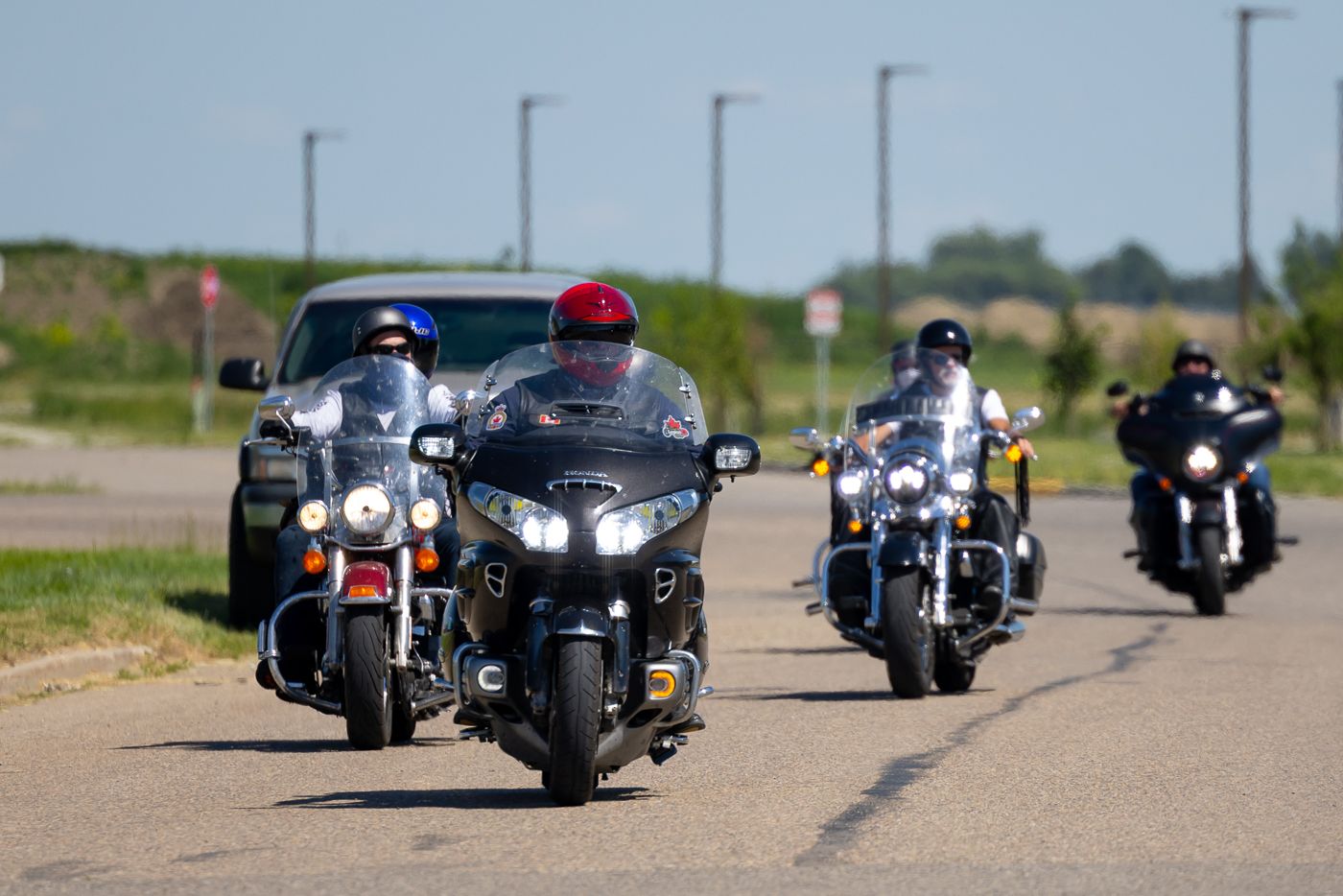 Group of motorcyclists riding in formation on a rural highway with motorcycles cruising together on a sunny day.