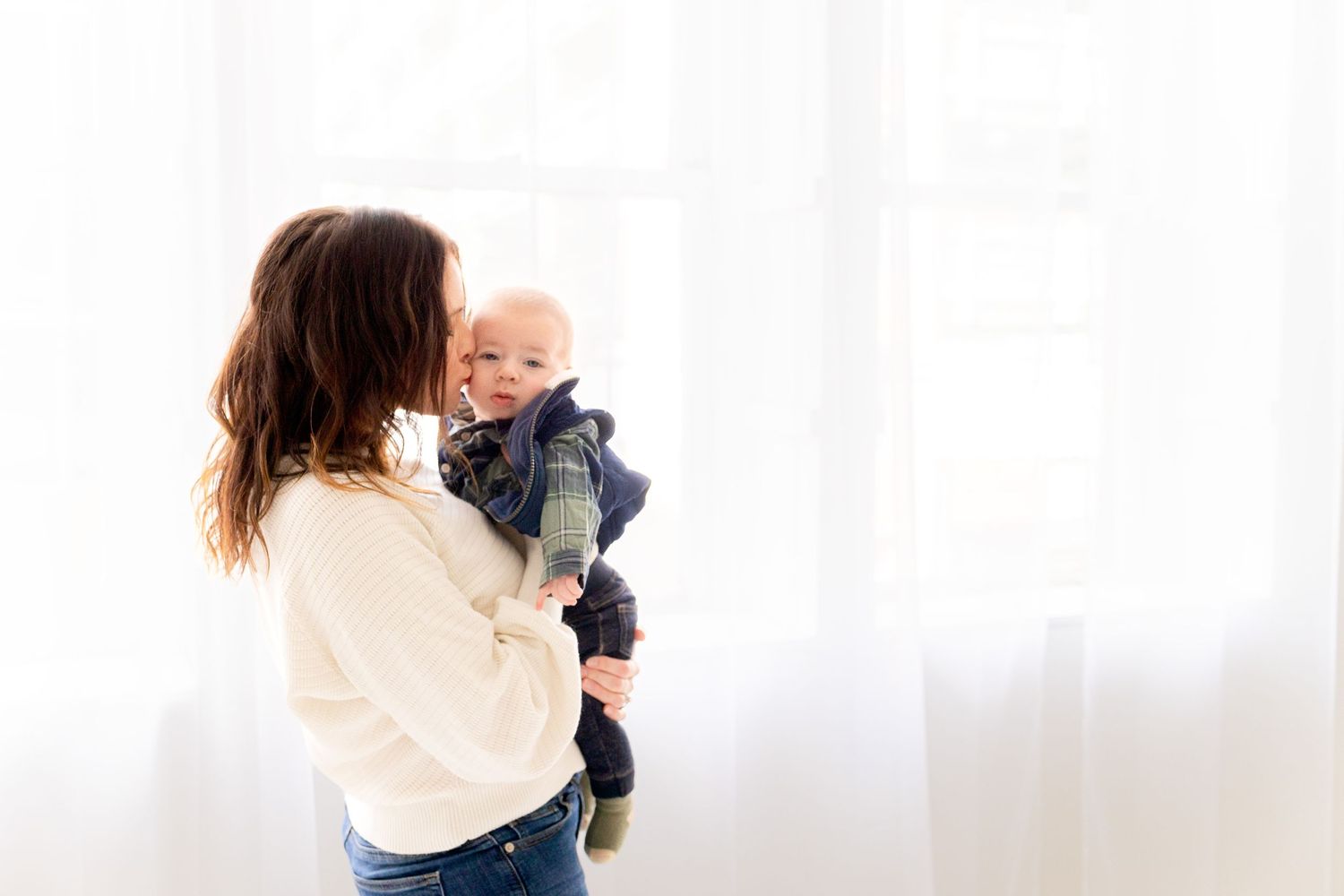 A tender moment between parent and baby against a bright white background.