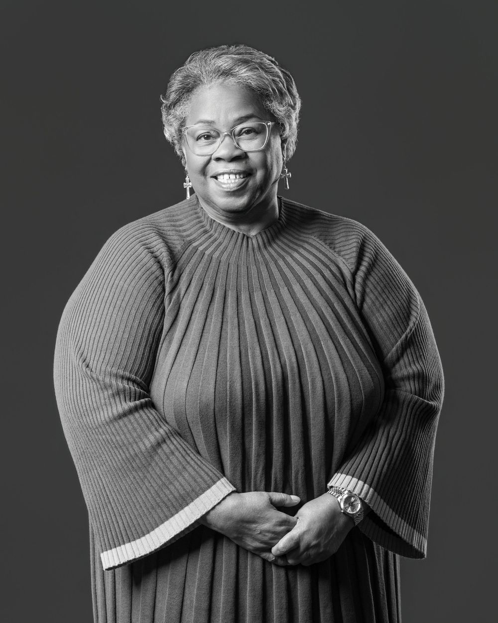 A series of black and white portraits showing a person in a ribbed sweater expressing different joyful emotions.