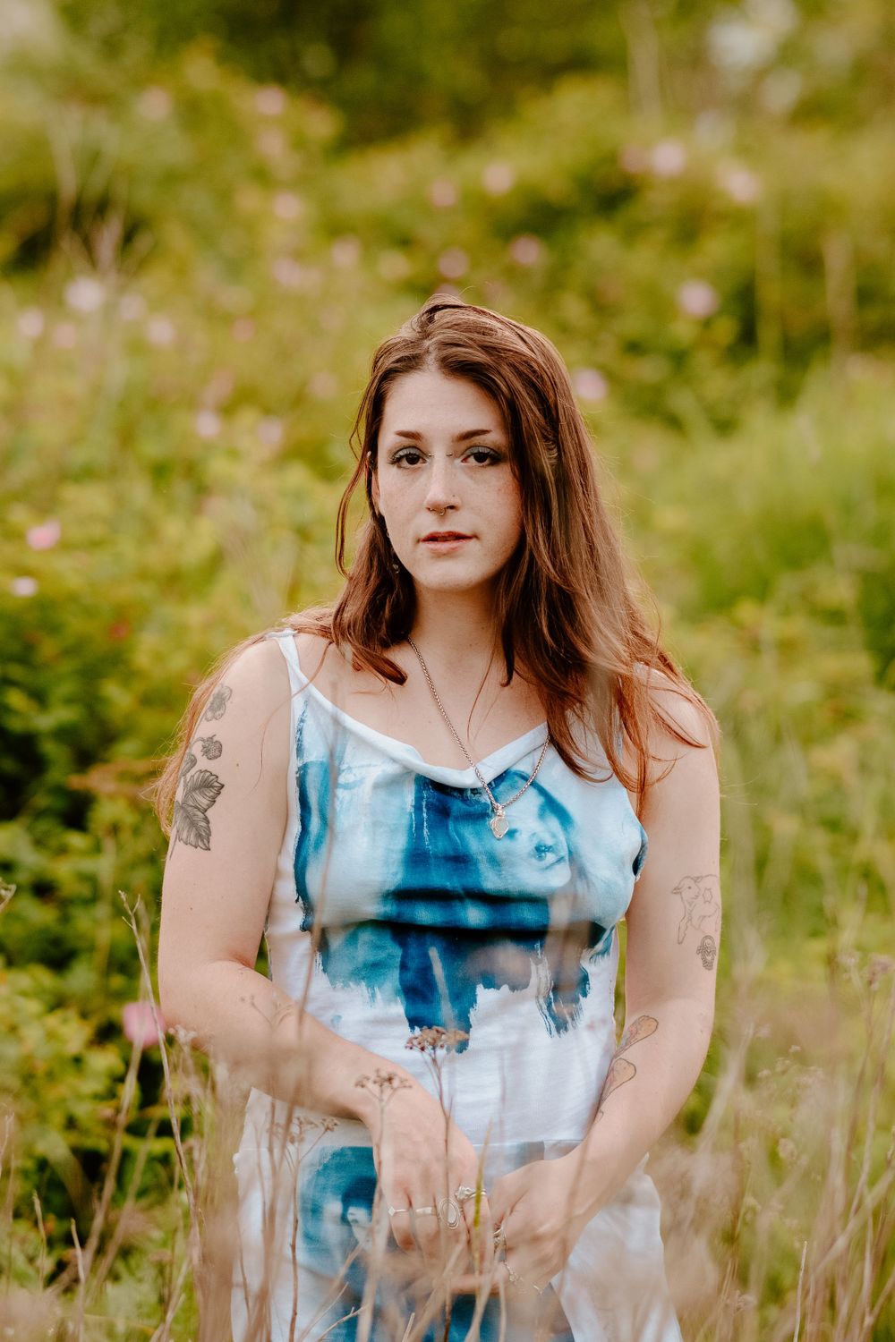 Summer portrait series in a meadow featuring a sleeveless blue and white dress design.