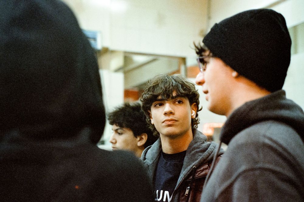 Group of young people in casual winter wear having a conversation indoors.
