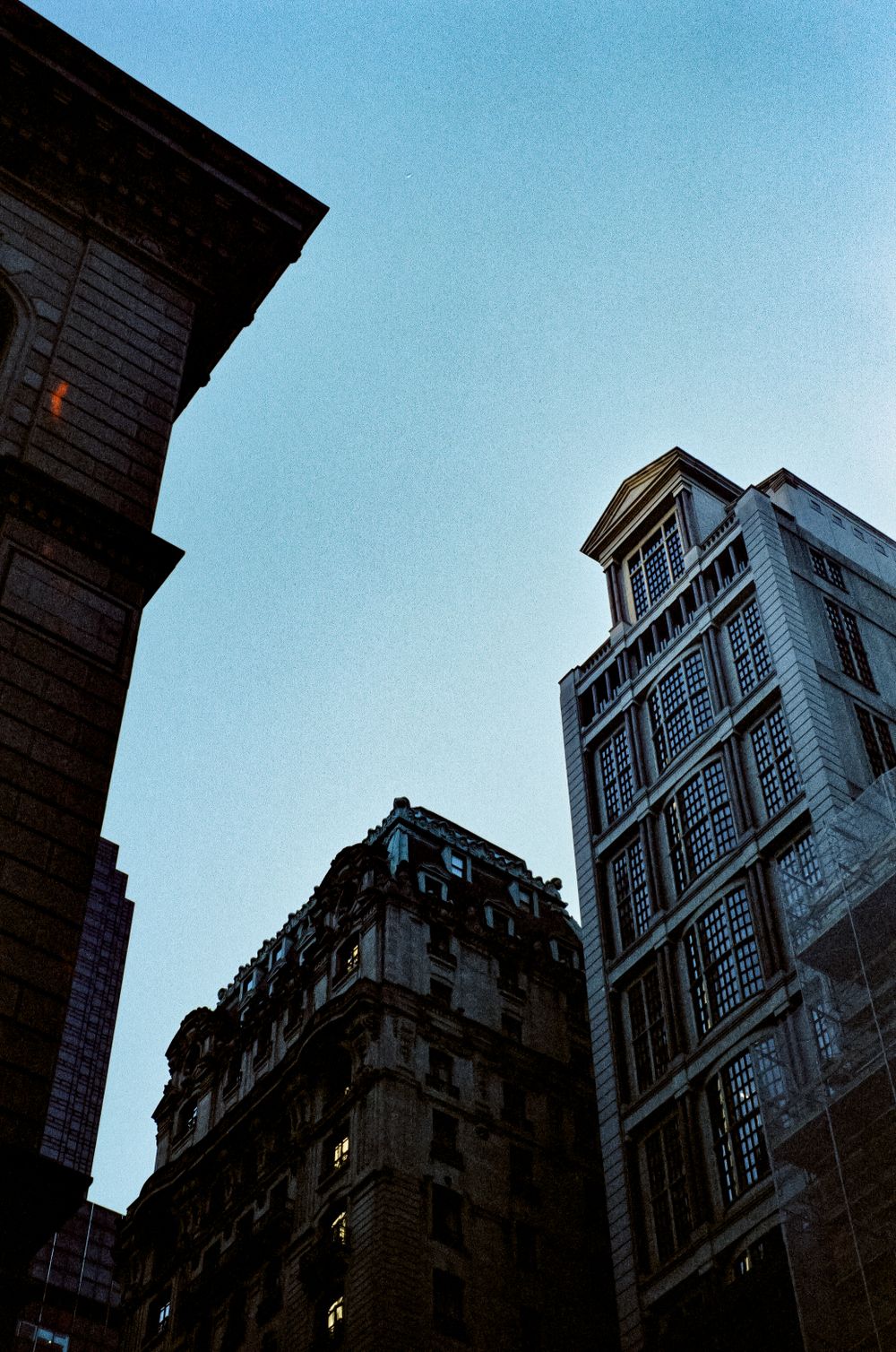 Low angle view of historic architecture and tall buildings against clear blue sky.