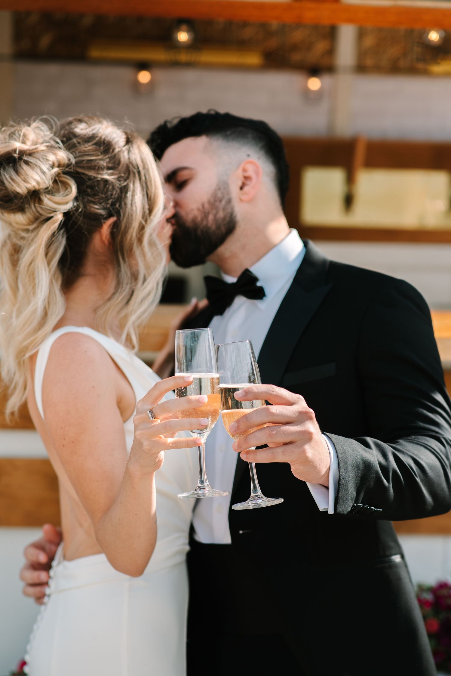 A wedding couple toasts with champagne glasses during their romantic celebration at an indoor venue.