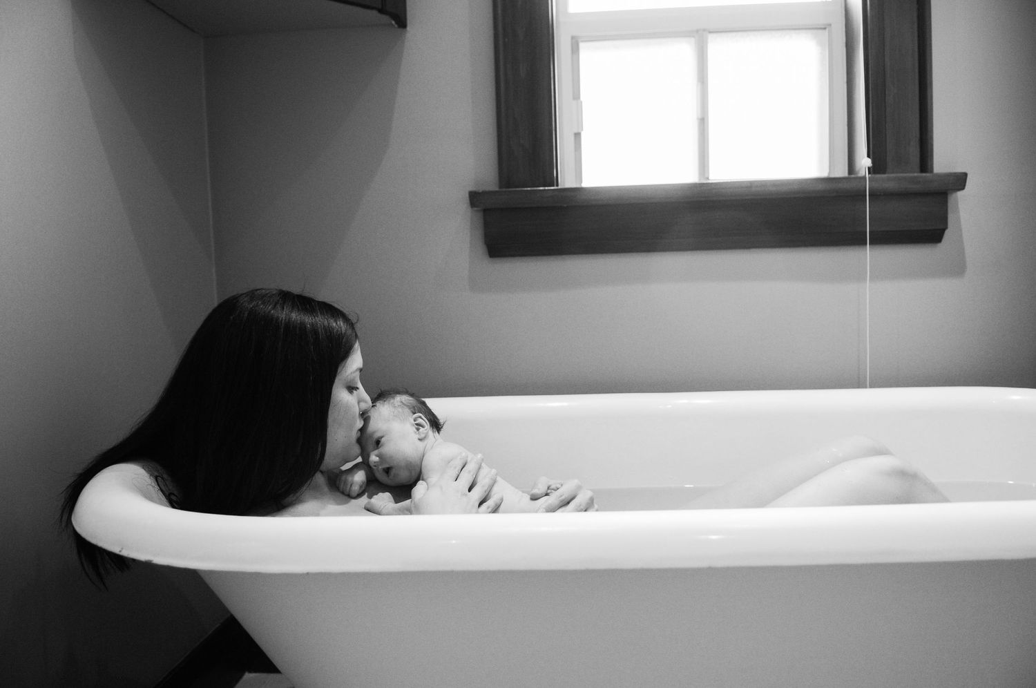 A black and white portrait of someone relaxing in a vintage bathtub.