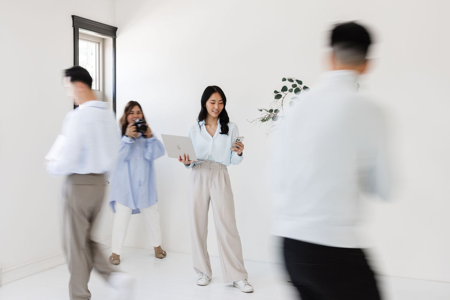 People in motion creating a blurred effect in a bright white studio space.