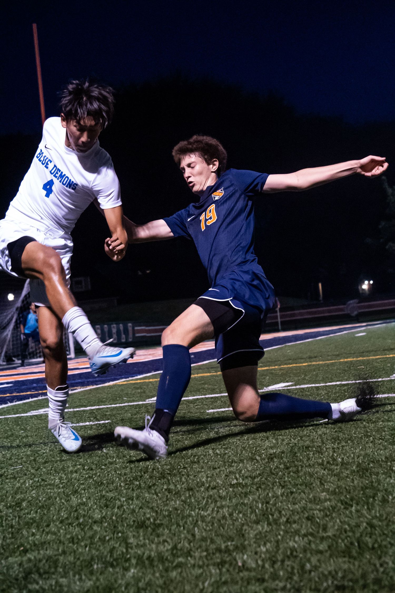 Soccer players competing for the ball during an intense match on a turf field at night.