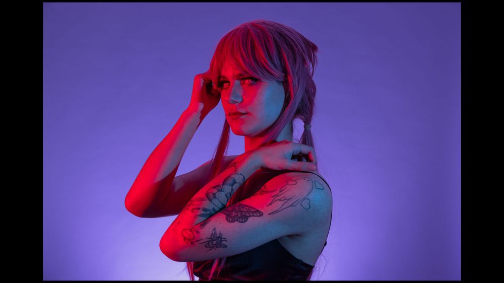Artistic portrait with purple and red lighting creating a neon atmosphere.