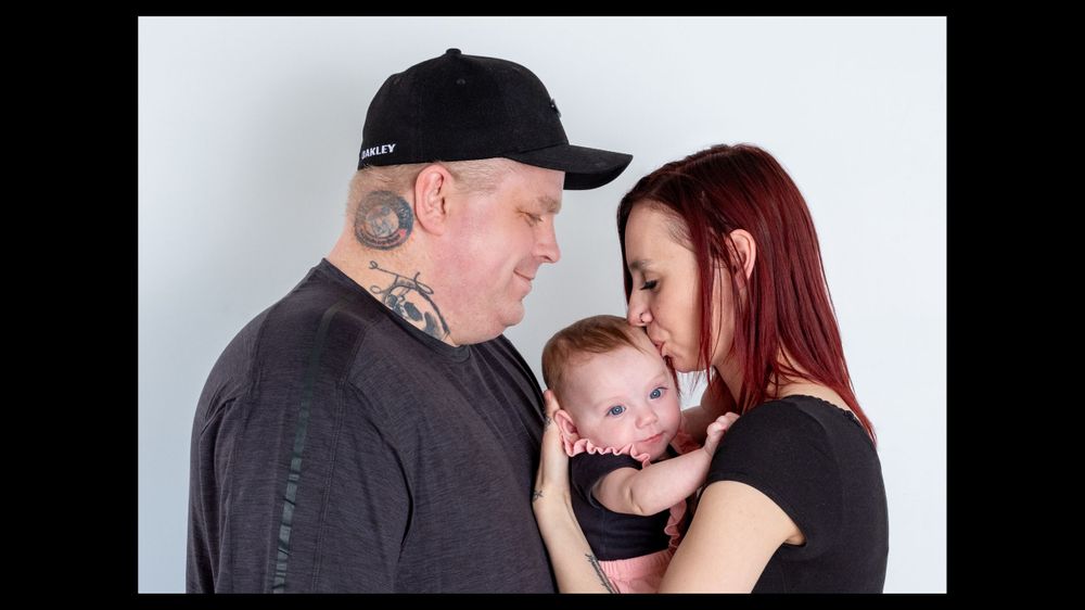 Family portrait with baby in black and white tones against light background.