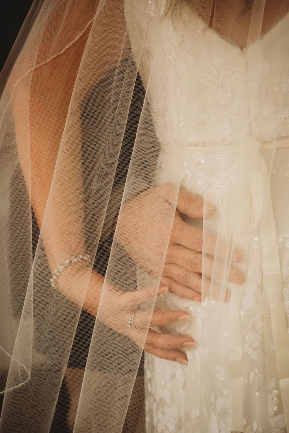 Bride and groom hold hands beneath brides veil Lafayette event space