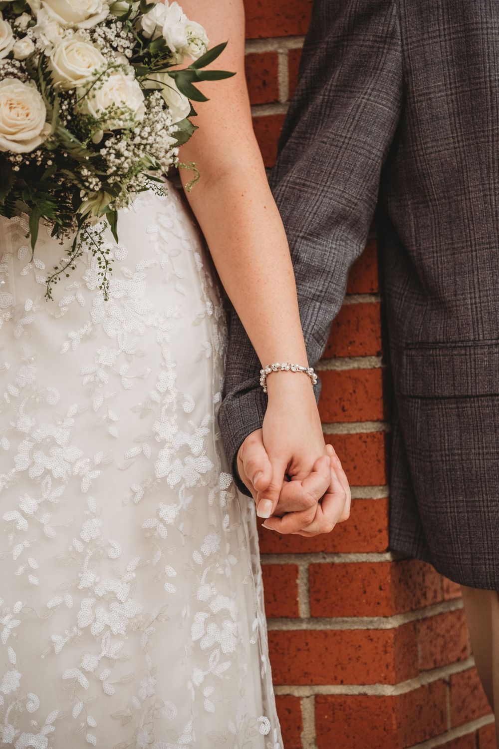 Bride and Groom holding hands brick wall Lafayette event space