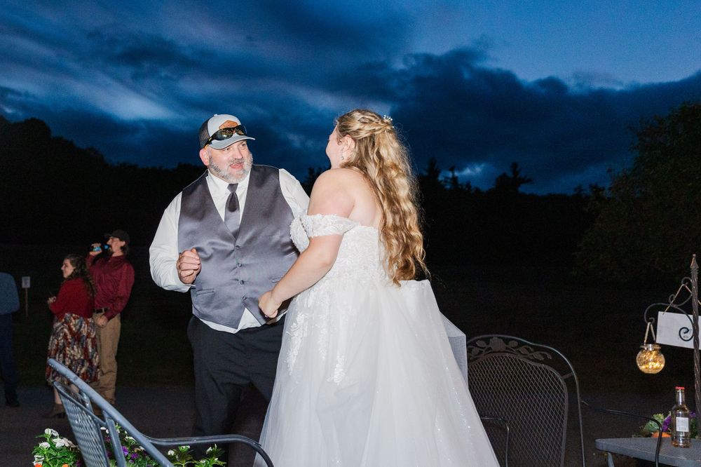 A couple dances together at twilight during their outdoor wedding reception.