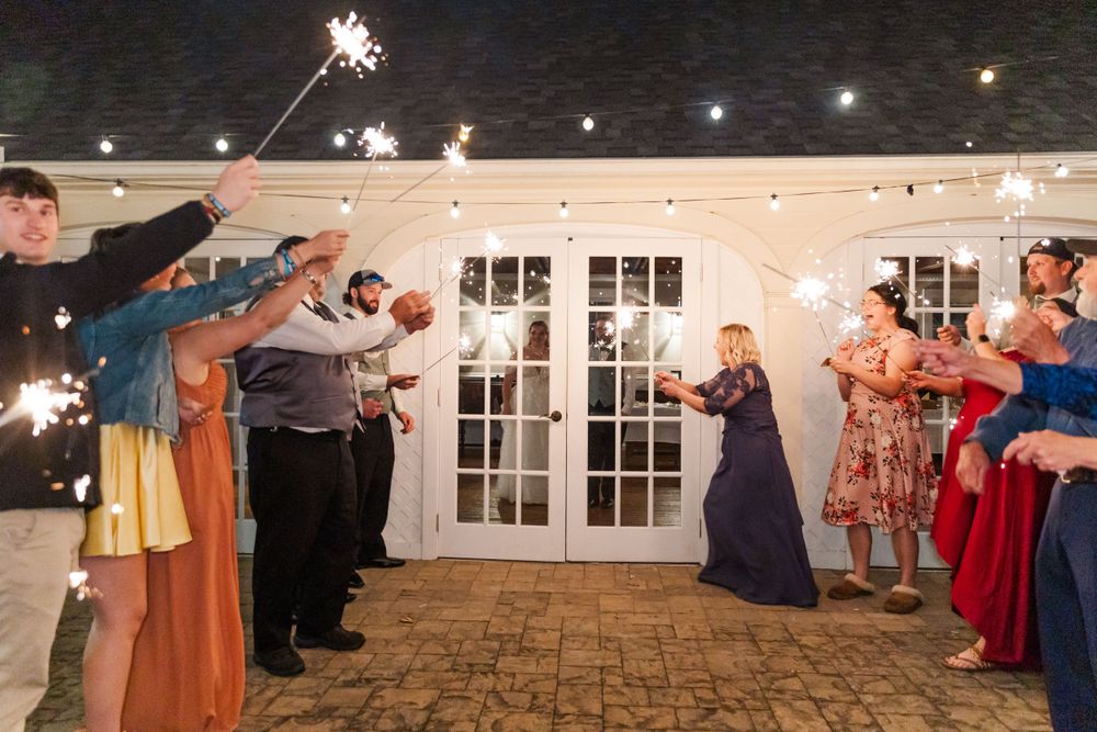 Wedding guests hold sparklers creating a magical exit tunnel for the newlyweds.