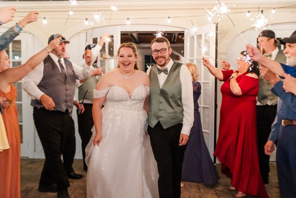 Newlyweds celebrate with guests holding sparklers during their wedding exit.