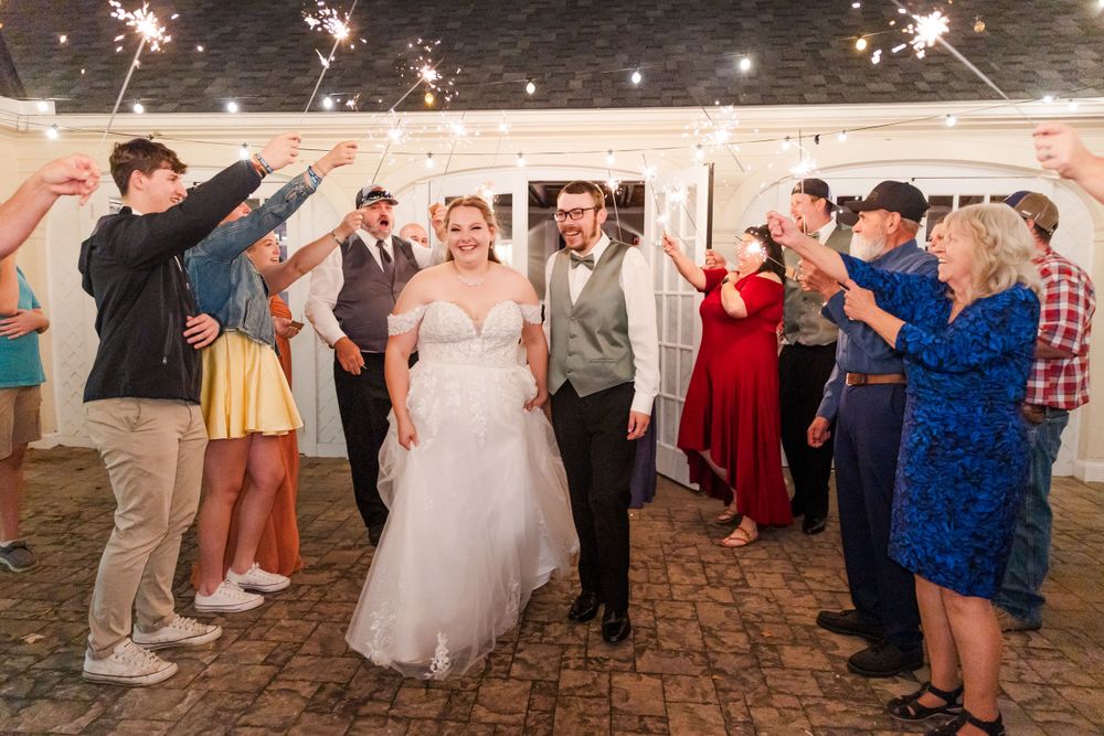 A wedding celebration with guests forming a sparkler tunnel for the newlyweds during an evening reception.