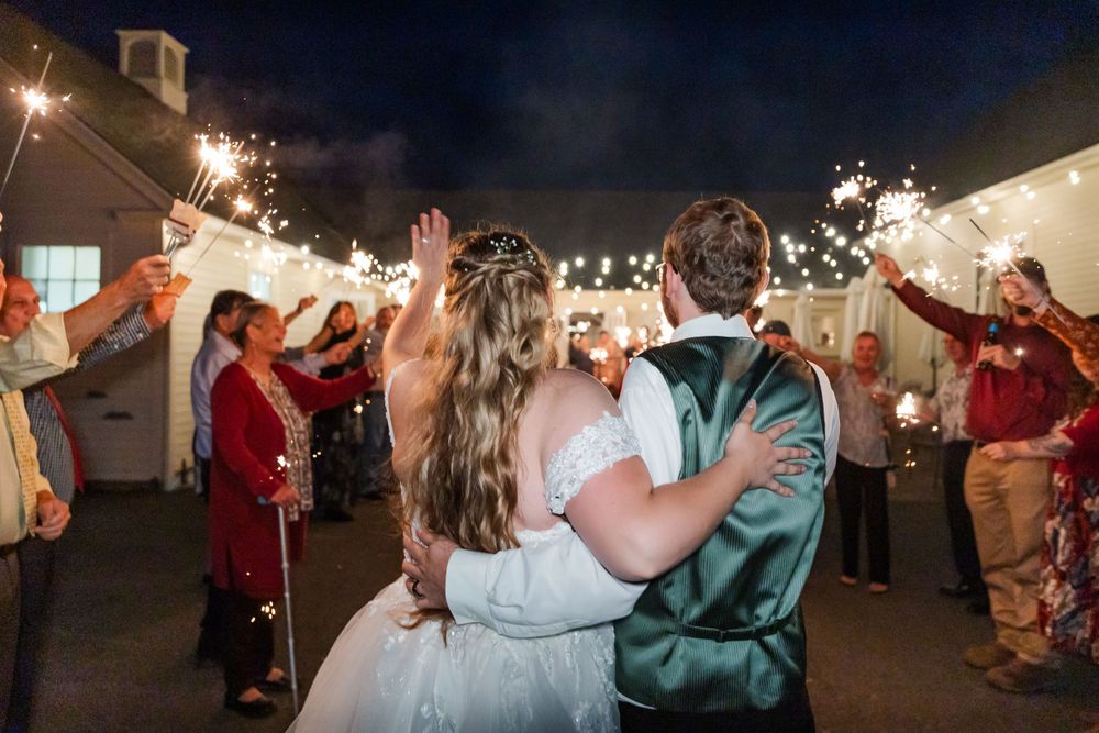 Wedding guests hold sparklers creating a magical nighttime exit for the celebrating couple.