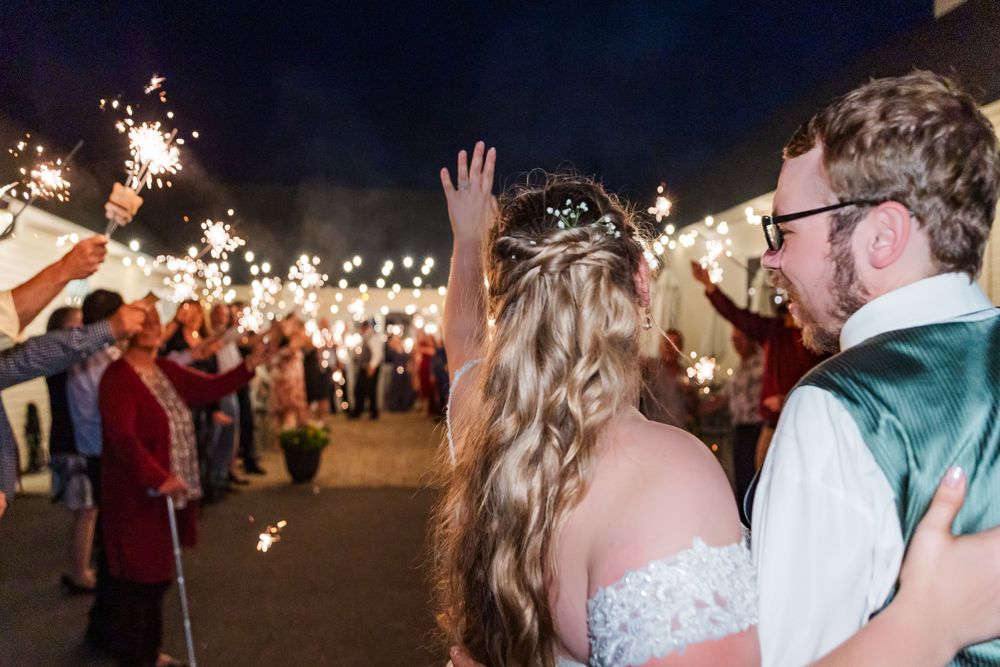 Wedding celebration under string lights with sparklers creating a magical nighttime atmosphere.