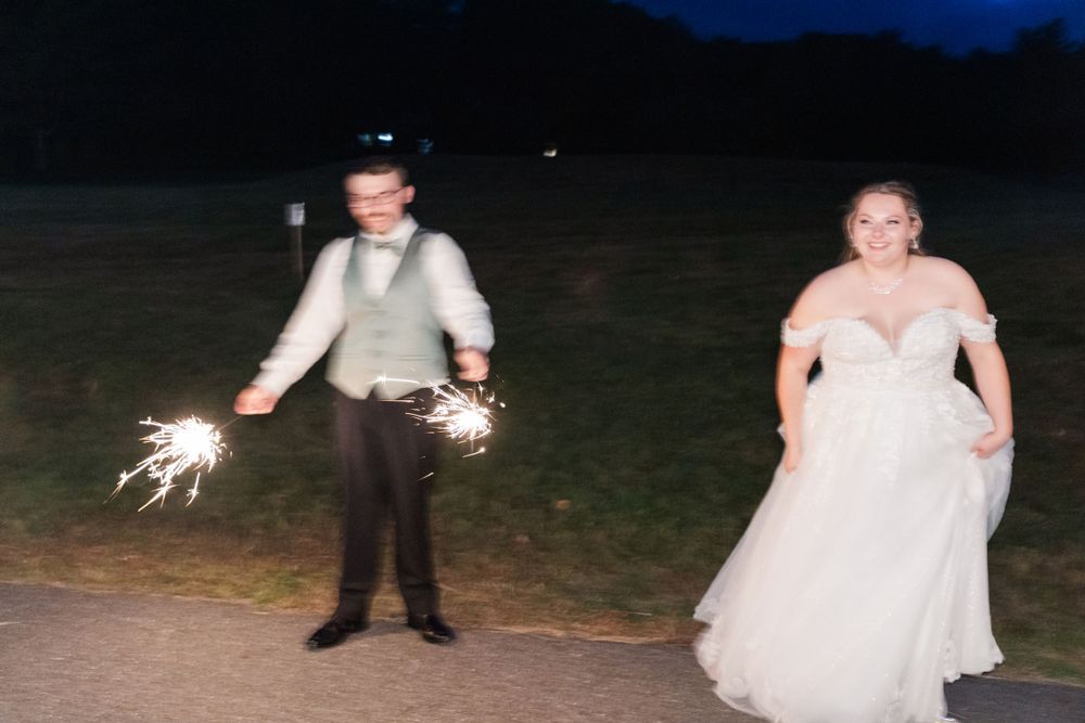 A playful moment with sparklers during an outdoor evening wedding celebration.