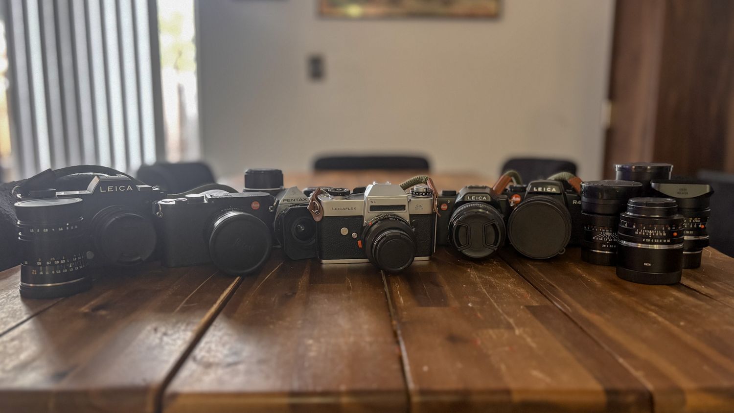 Vintage photography equipment lined up on wooden table surface.