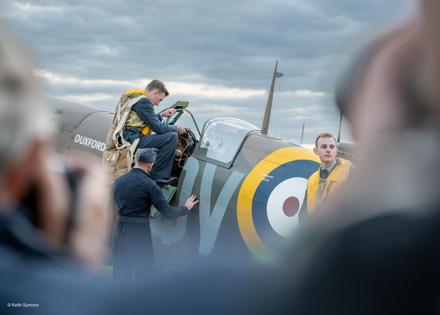 People gathered around a vintage military aircraft at an airshow.