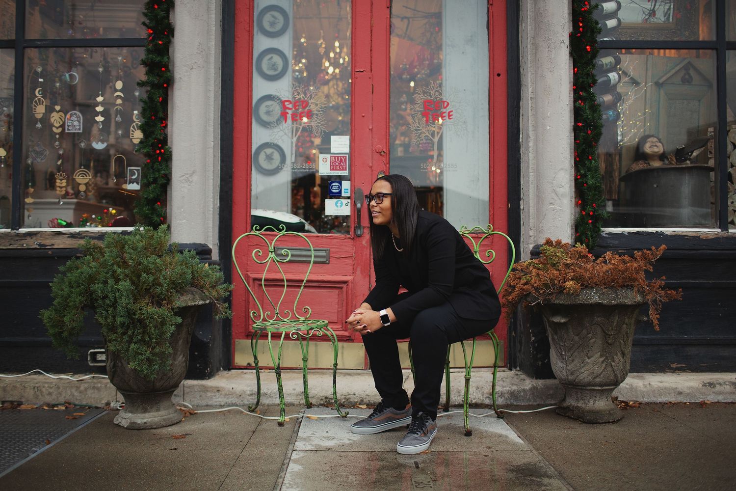 photo of a girl sitting on a green metal chair in front of red tree gallery nulu louisville ky