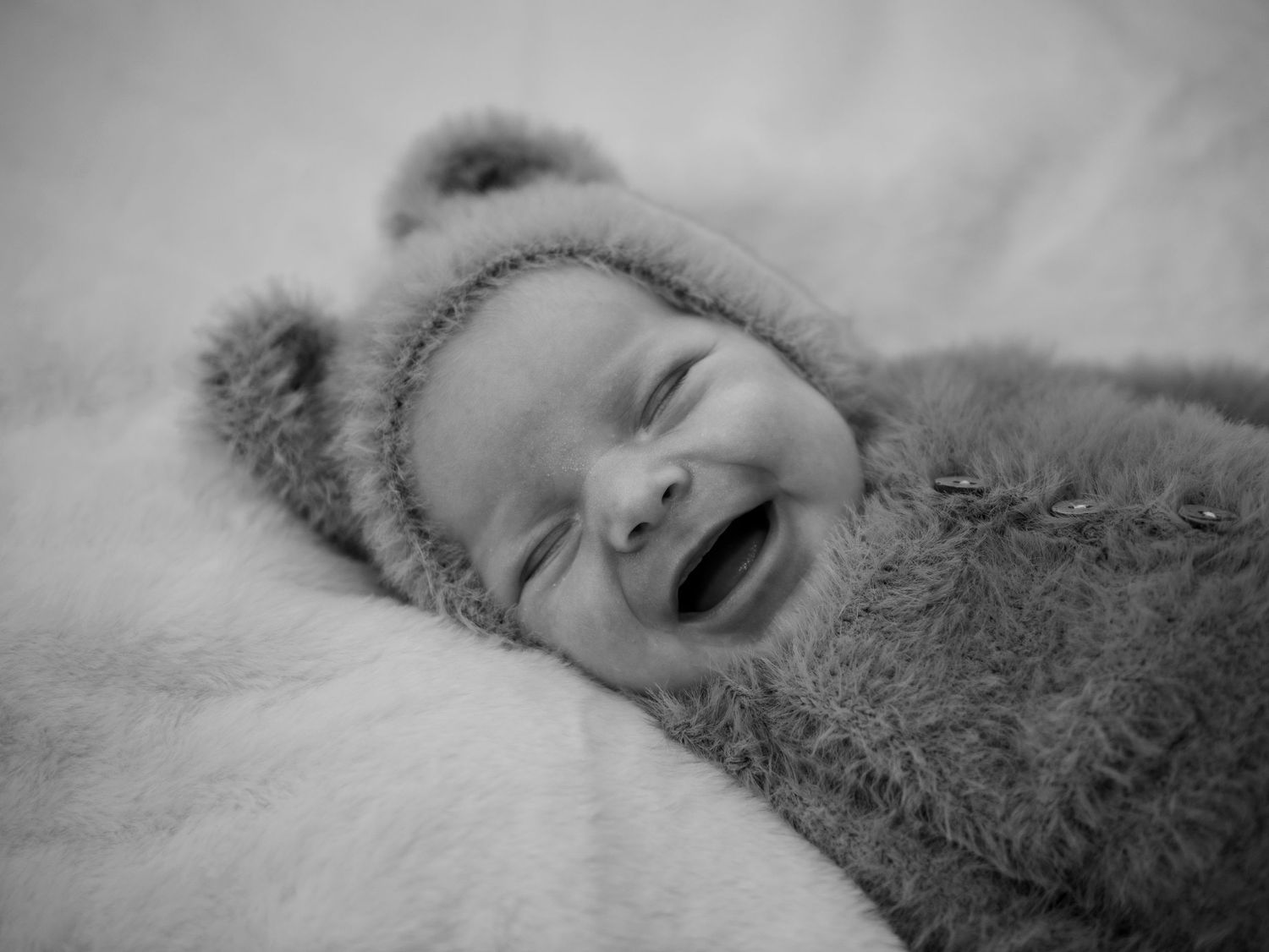 Close up black and white image of sleeping baby on soft textured blanket. Teddy Bear Newborn