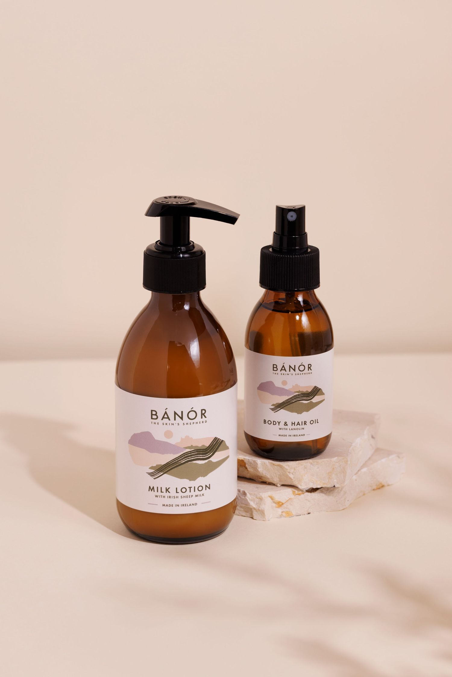 Two amber glass bottles of Banor skincare products with pump and spray dispensers on neutral background with soft Leafy shadows.