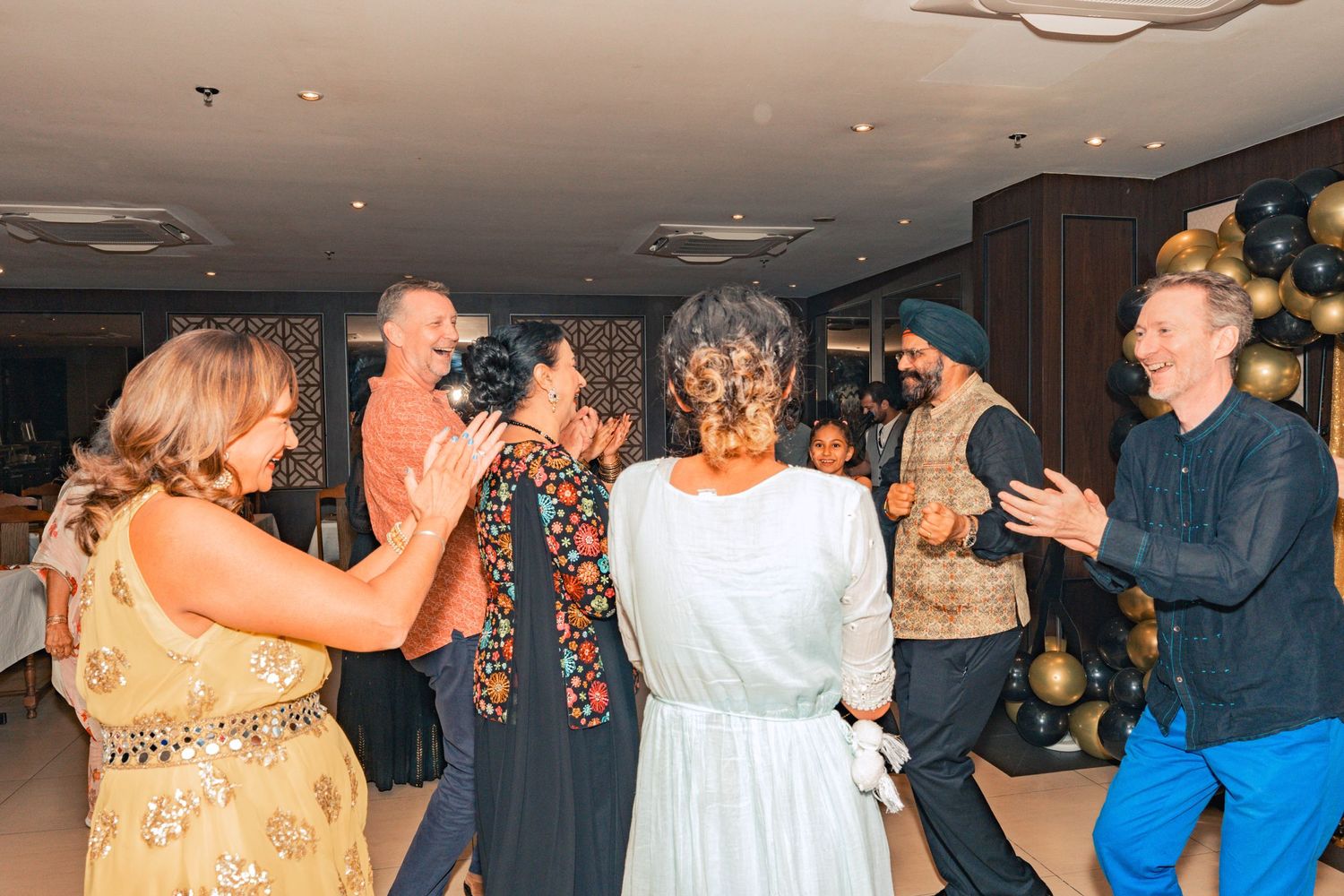 Party guests dance together under ceiling lights with festive decorations.