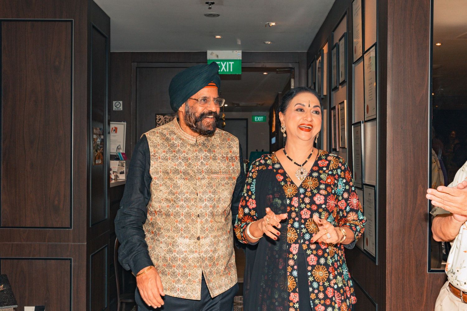 Couple in traditional Indian formal wear walking through an indoor venue hallway.