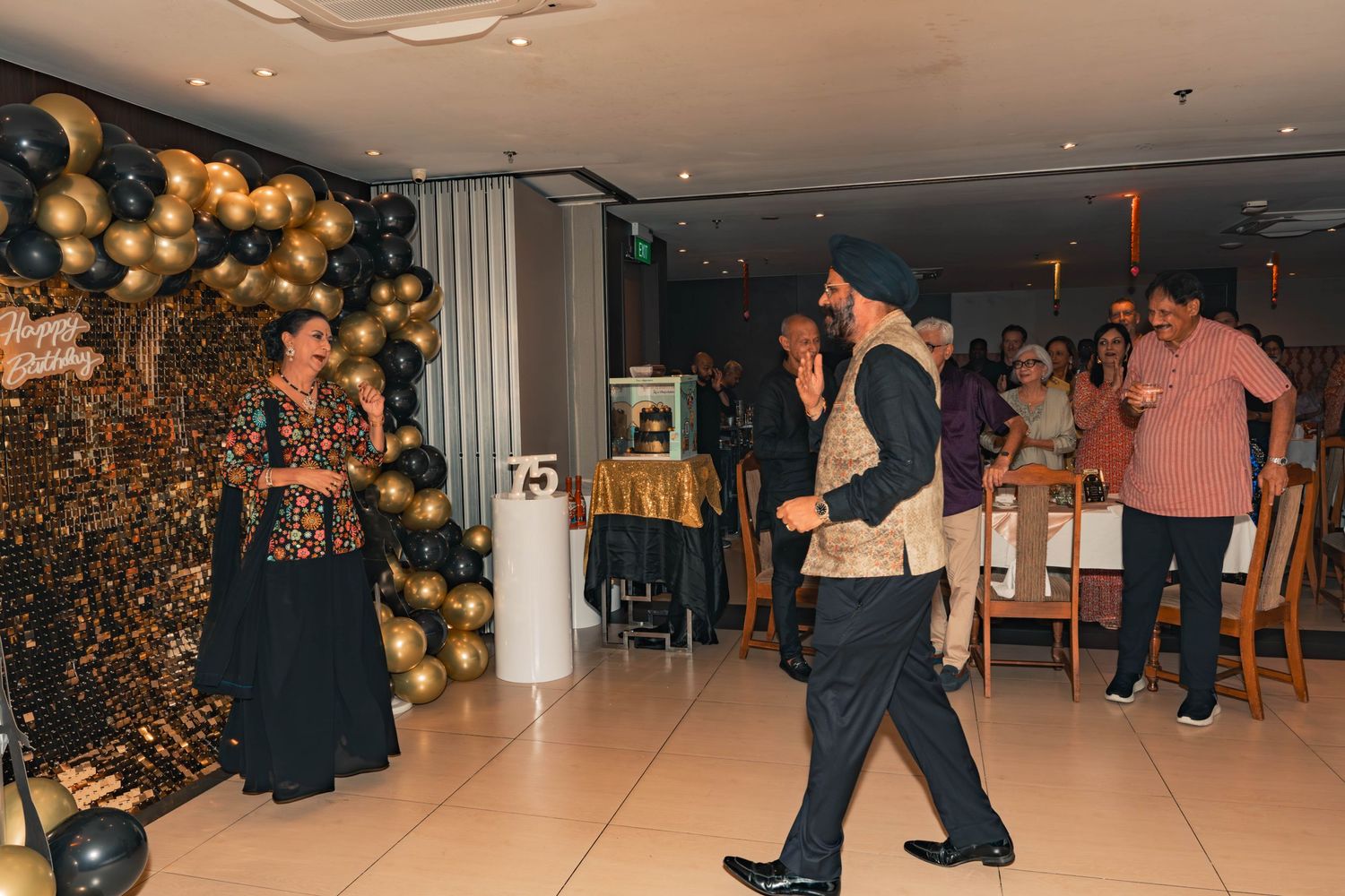 Event celebration with gold and black balloon decorations as guests dance.