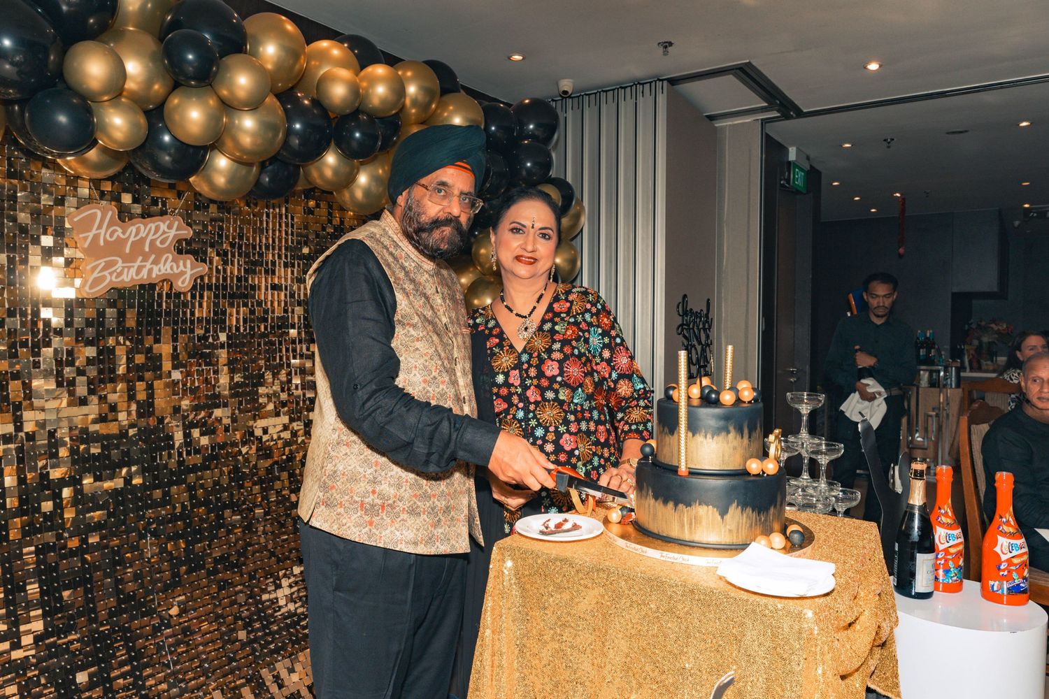 Elegant party scene with gold sequin backdrop and balloon decorations.