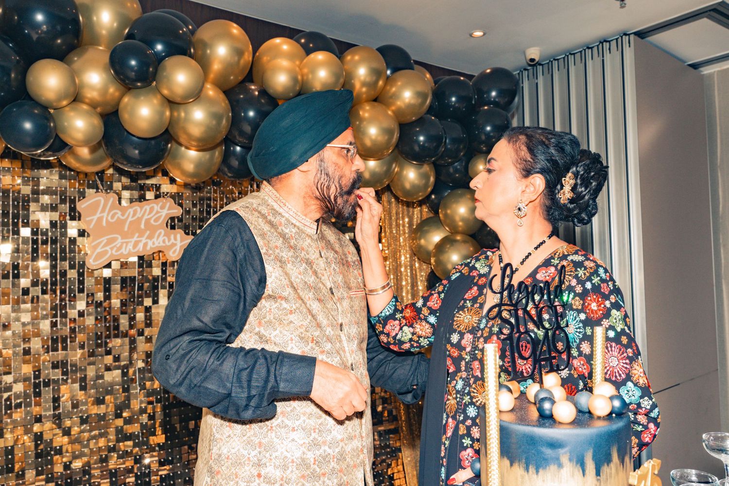 Festive moment shared under gold and black balloon arch decorations.