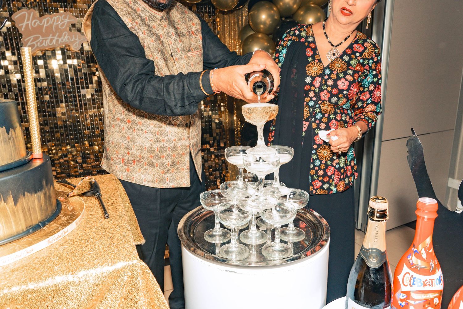 Pouring champagne into a tower of glasses at an elegant celebration.