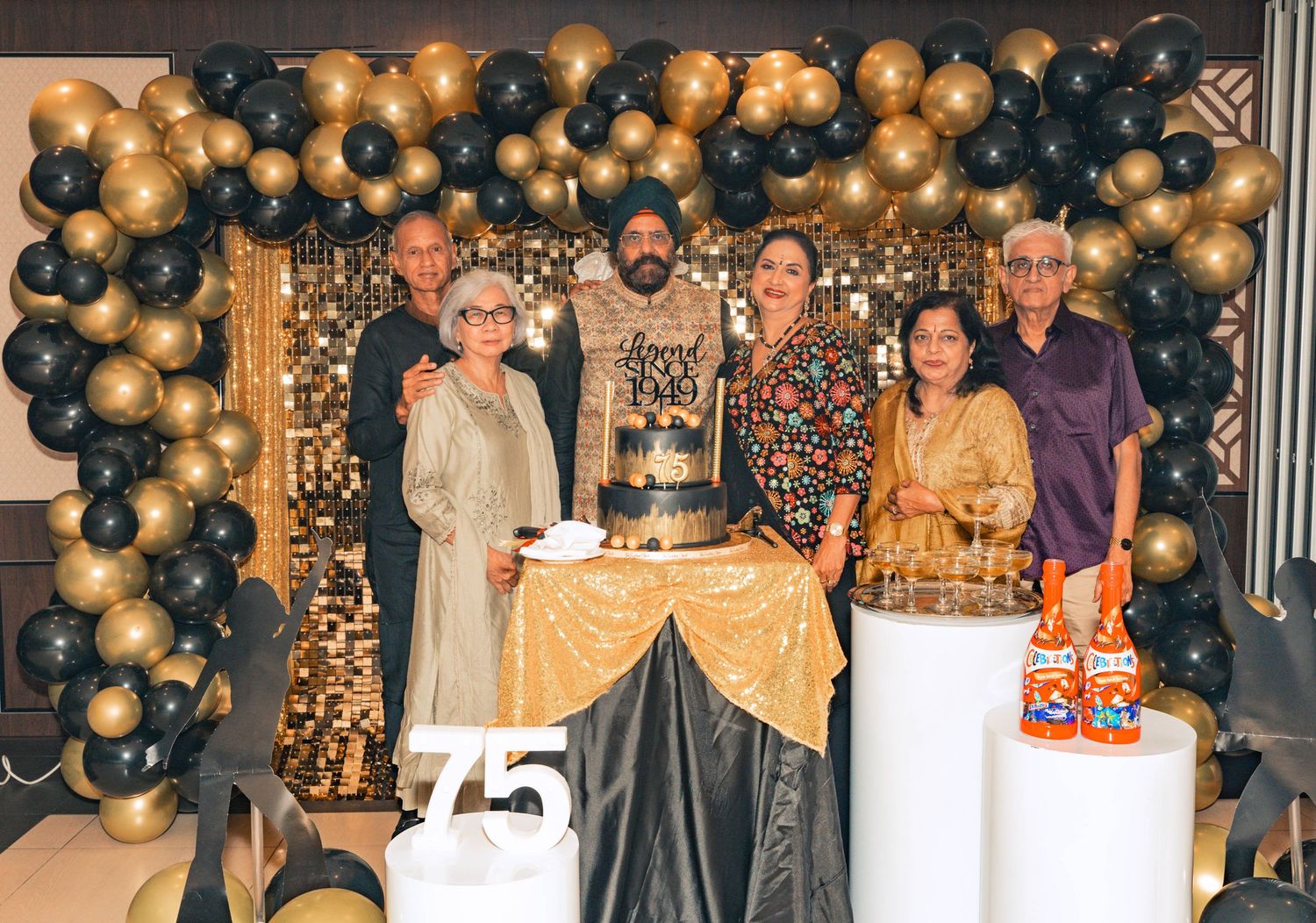 Group photo with elegant balloon arch and tiered cake display.