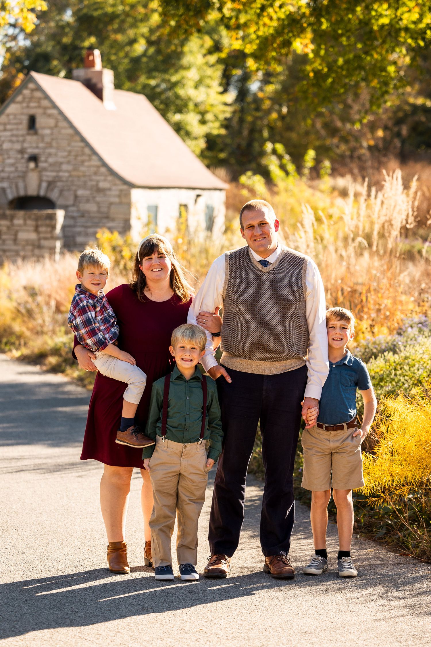 Family walking together on path with autumn foliage in background.