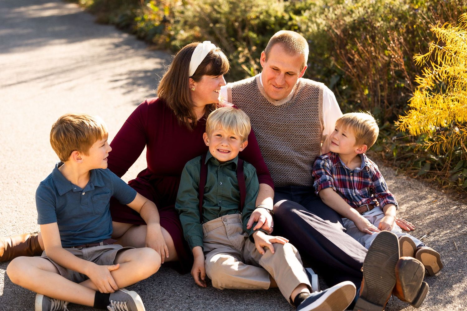 Family relaxes together on ground during outdoor autumn photoshoot.