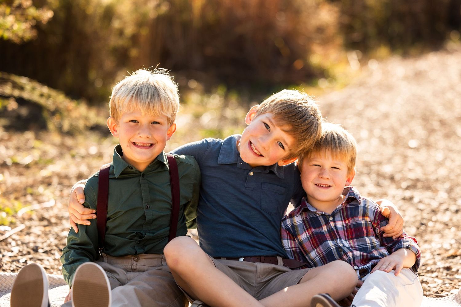 Children sitting close together outdoors during fall photo session.