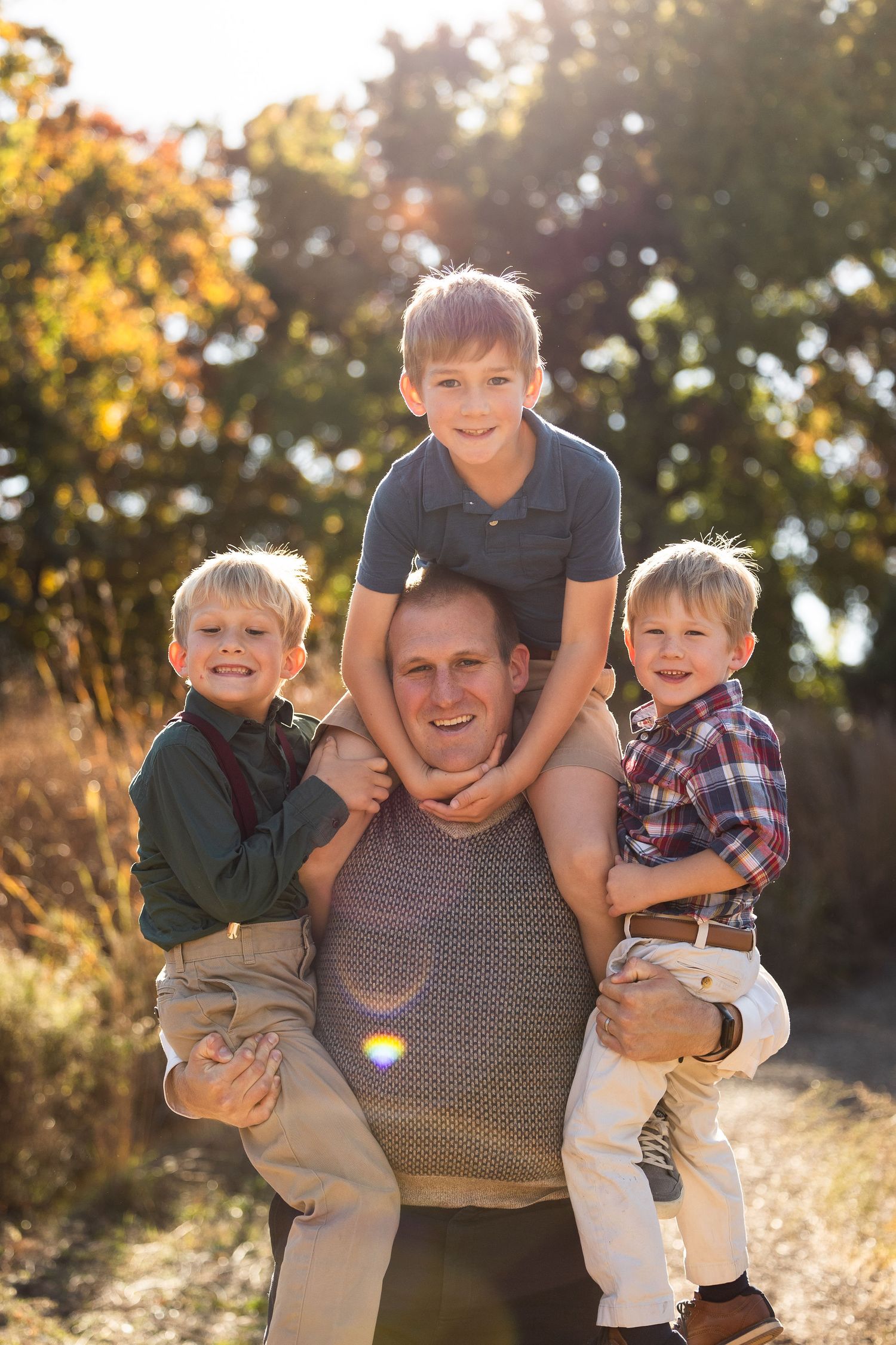 Parent holding children during playful outdoor family photoshoot.