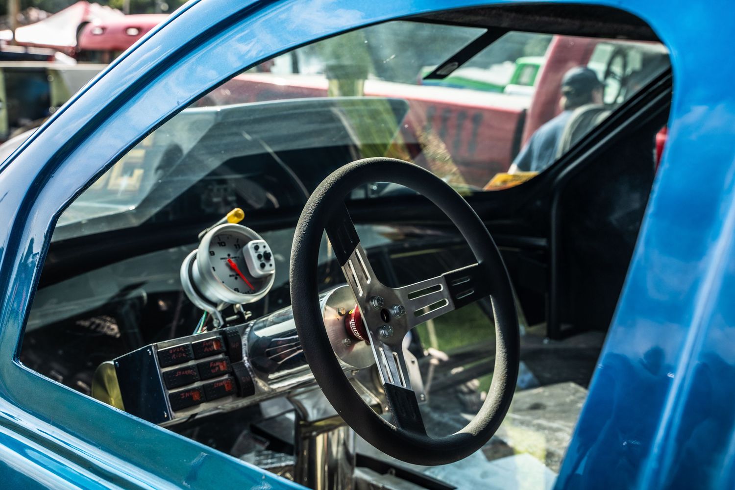 Interior dashboard view of classic car showing vintage steering wheel and gauges.