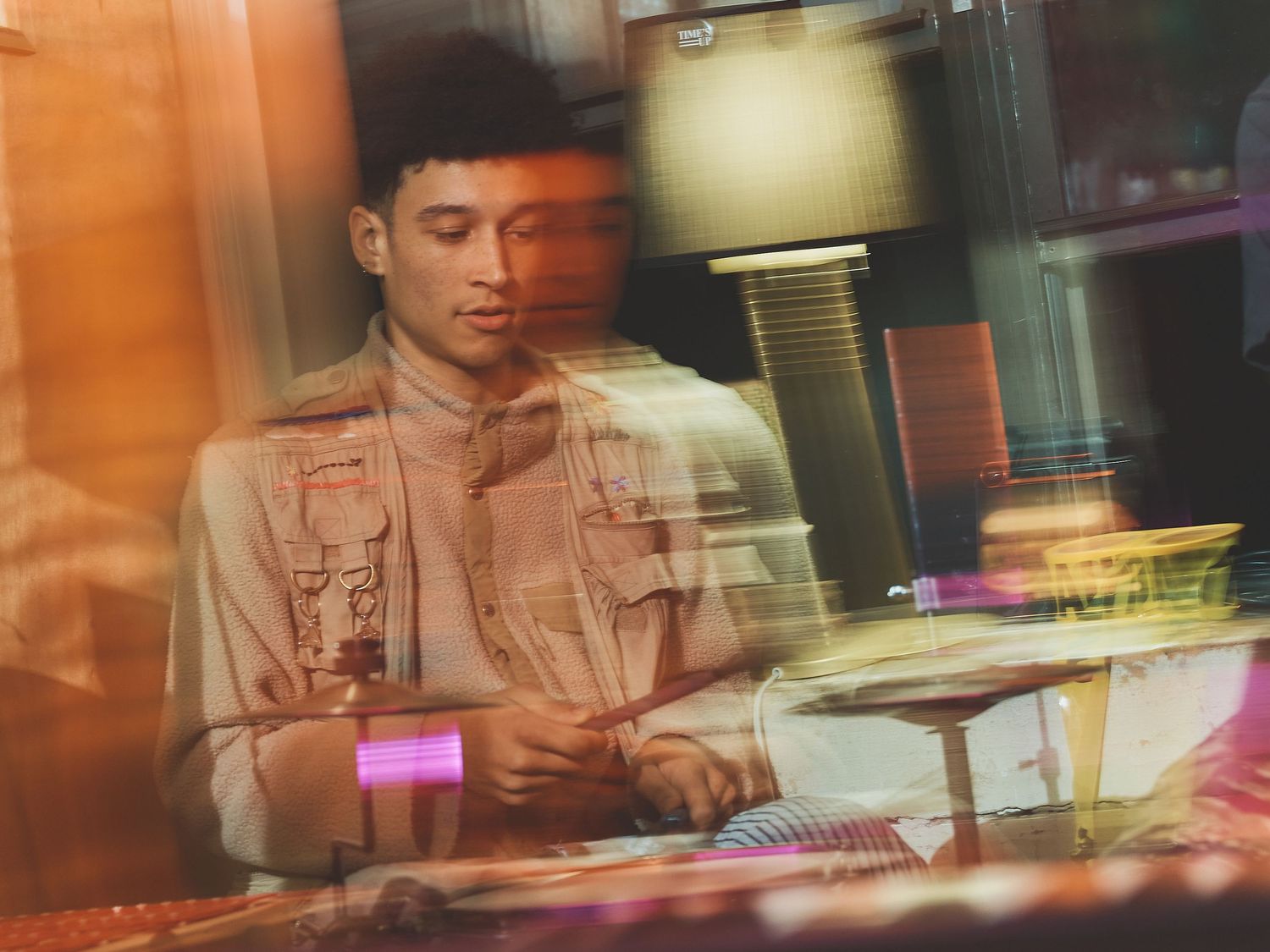 Candid performance shot with orange ambient lighting and reflective surfaces creating depth.