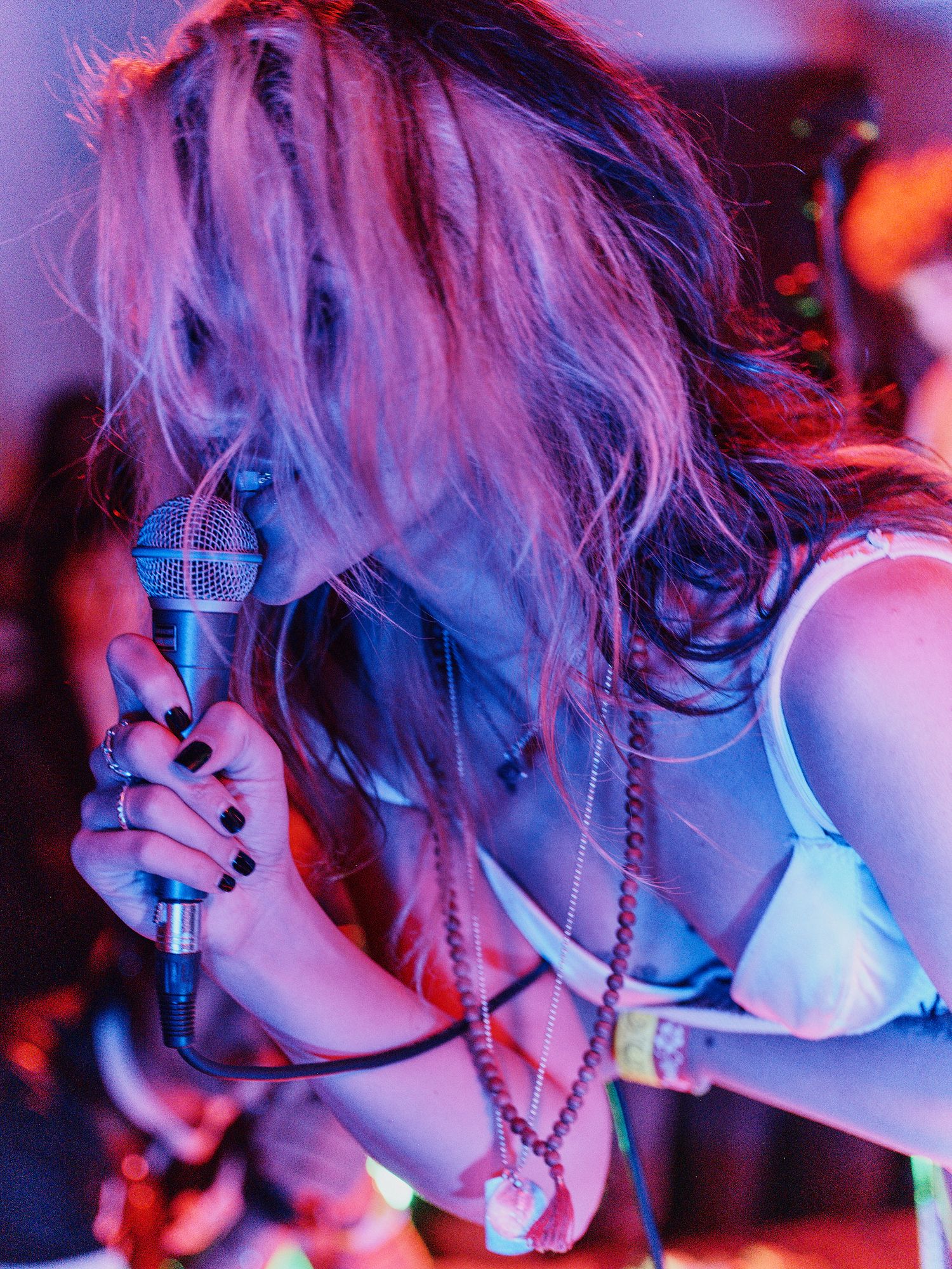 Atmospheric concert performance bathed in vibrant red and blue stage lighting shows silhouetted performer singing into microphone.
