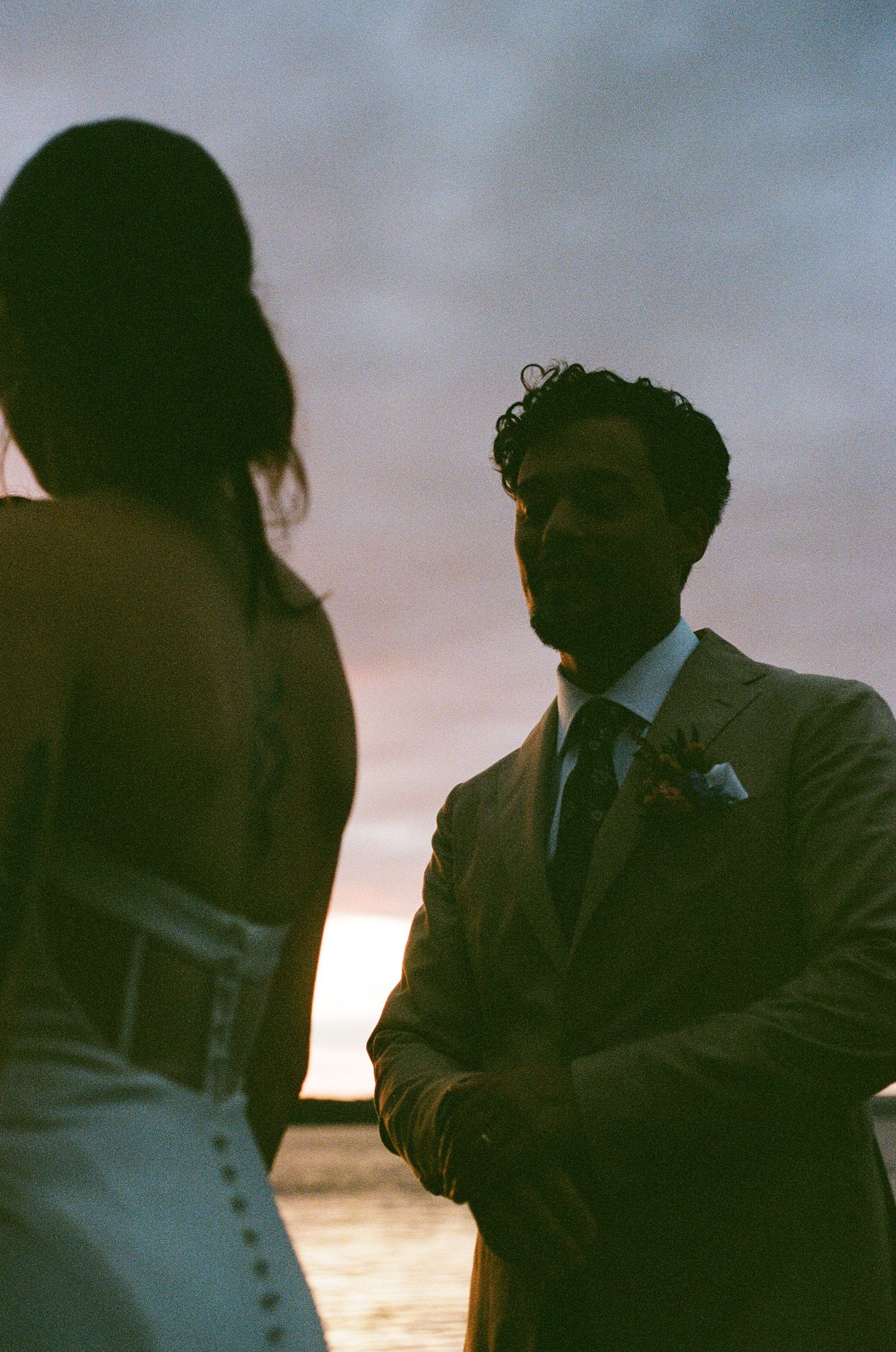 Romantic silhouette of newlyweds against a sunset sky during an outdoor wedding ceremony.