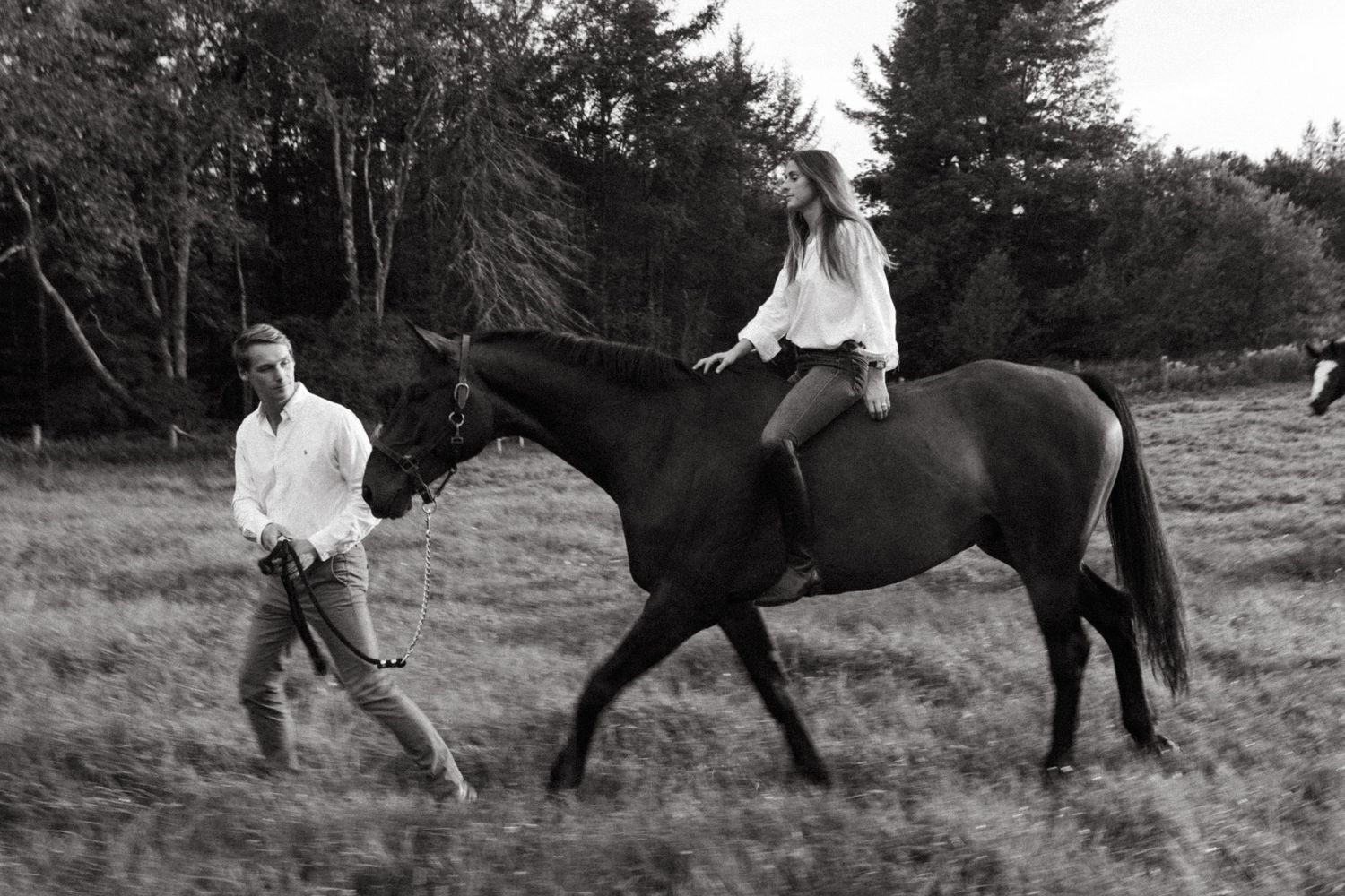 Casual countryside scene with horse riding and walking in black and white.