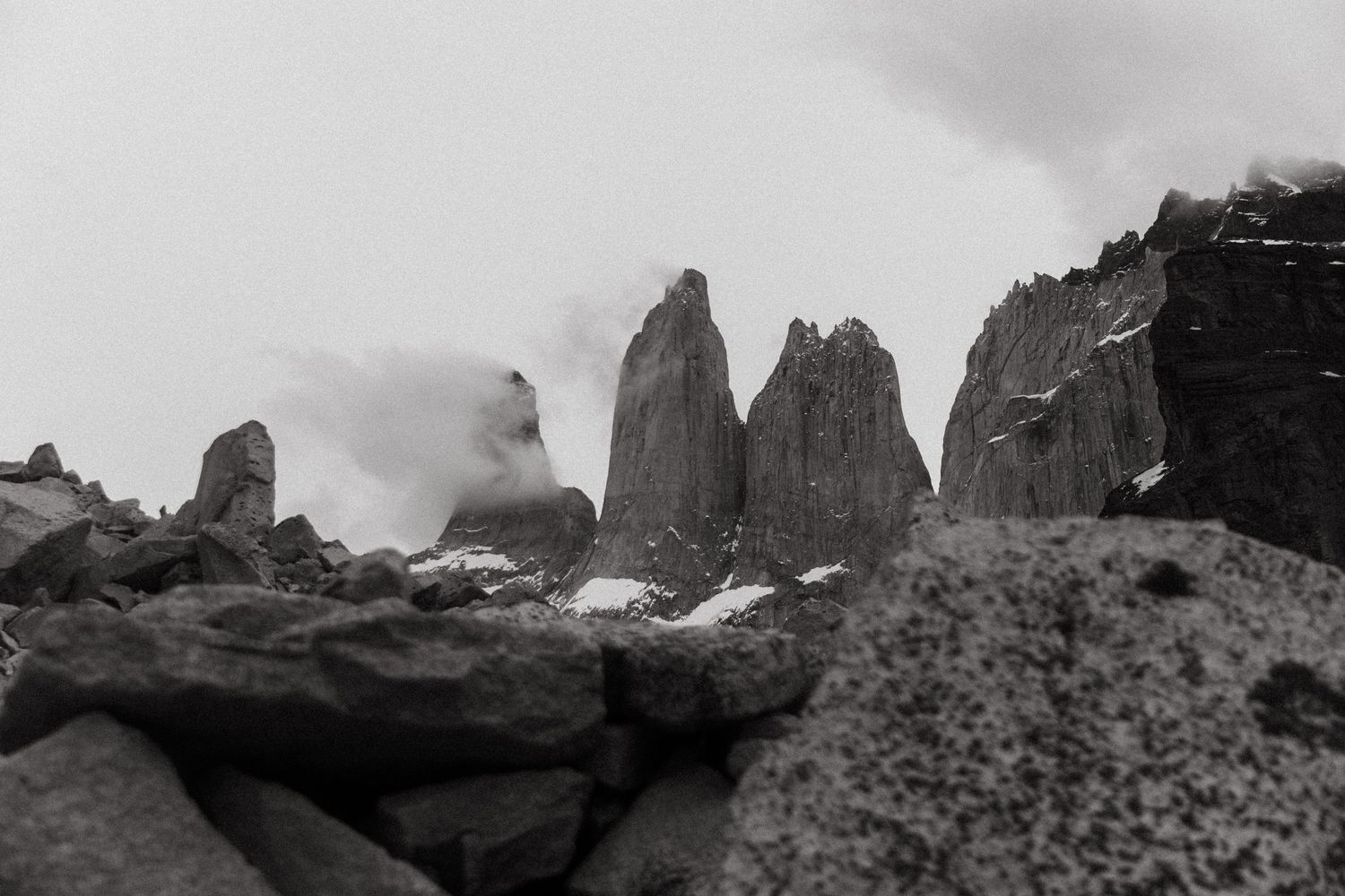 Dramatic black and white landscape of jagged mountain peaks emerging through misty clouds.
