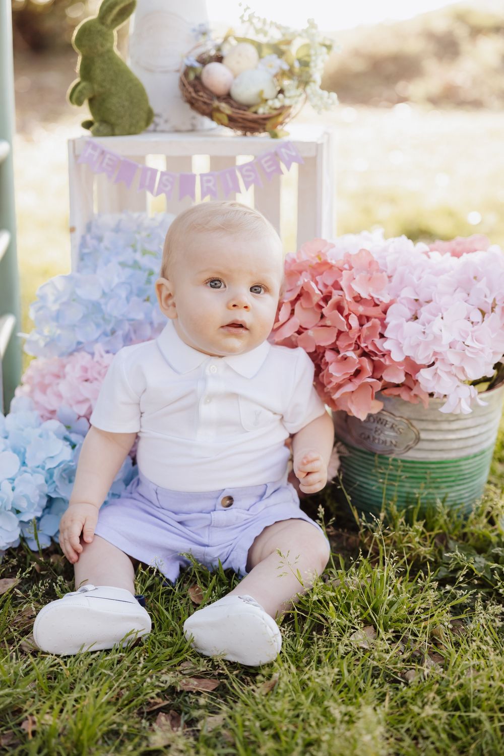Sweet Easter portrait setup outdoors with pastel hydrangeas, white bunny decor, and vintage-style spring outfit.