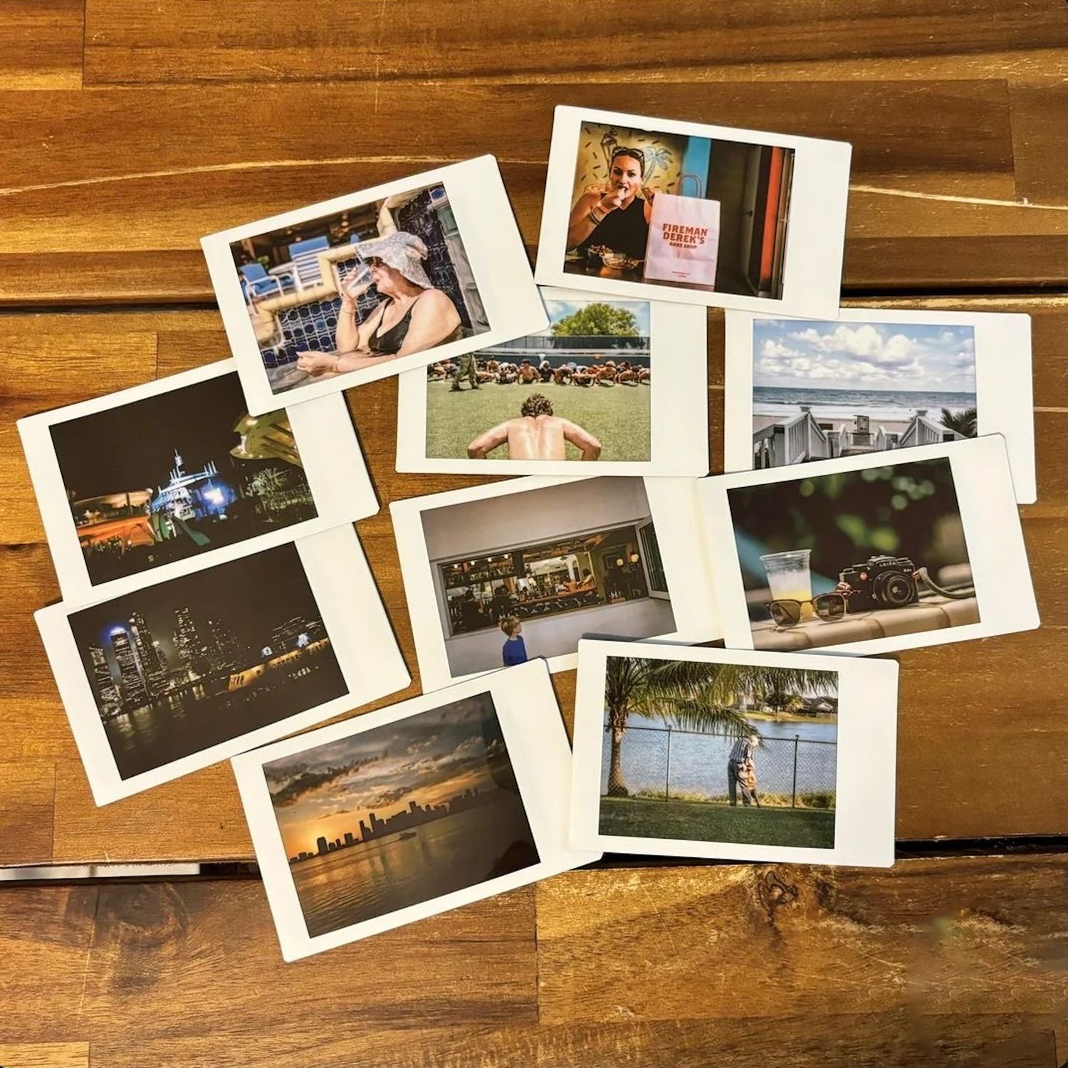 Collection of travel photographs spread out on a wooden surface showing cityscapes and scenic views.