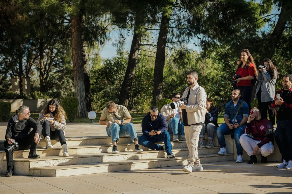 People sitting and relaxing on concrete benches in a sunny park area during a warm day.