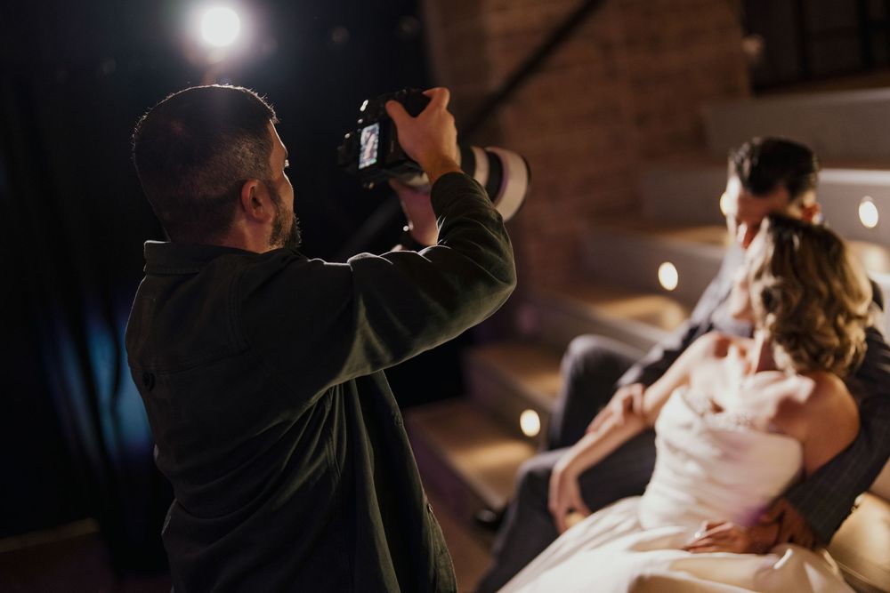 Professional photographer captures a candid moment of a bride in a white wedding dress during an evening reception.