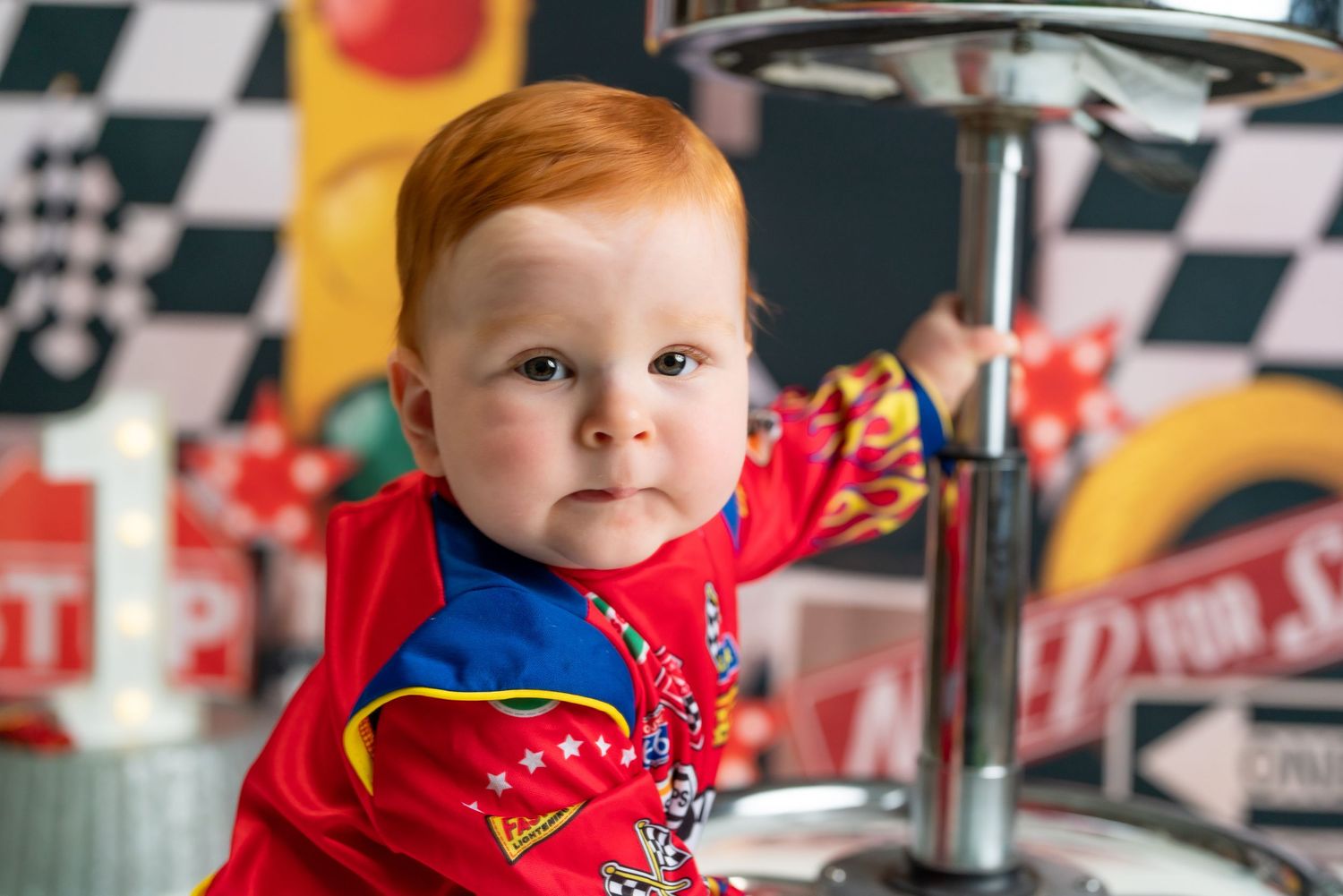 A young child in a red sweater sits at a counter in a checkered racing-themed environment.