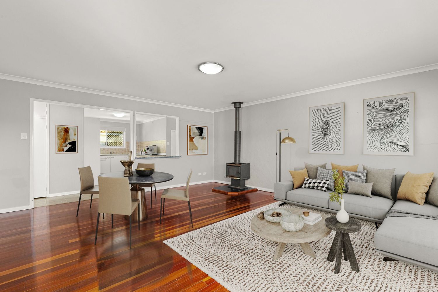 Classic living and dining room with polished hardwood floors, wood-burning fireplace, crown molding, and neutral decor.