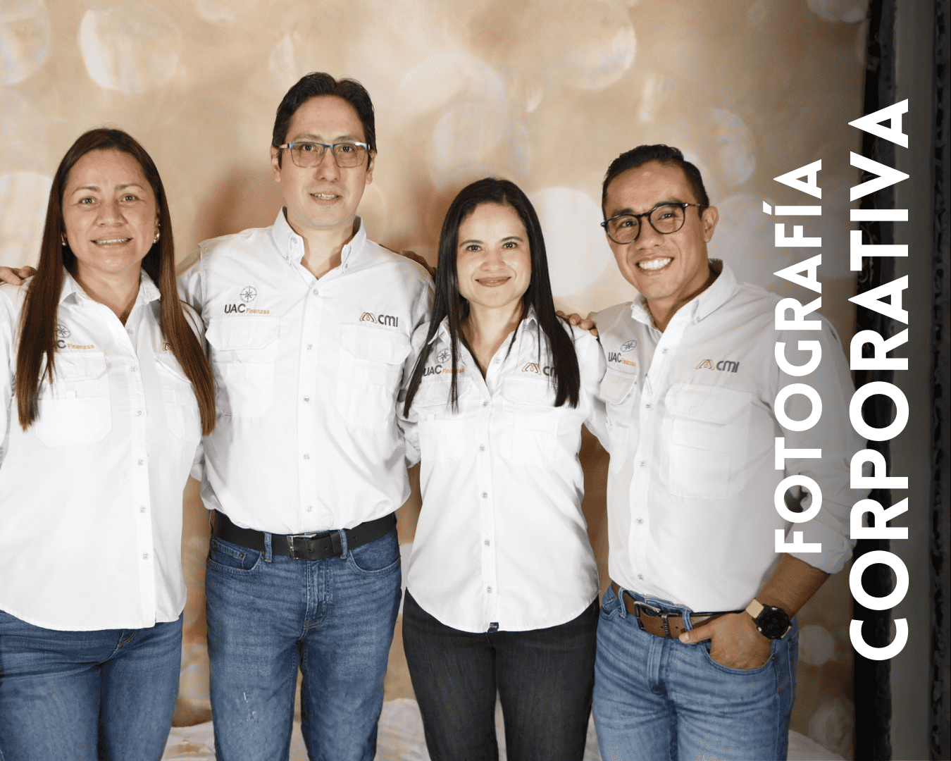 A group of people wearing white polo shirts and jeans standing together in a row against a light colored wall.